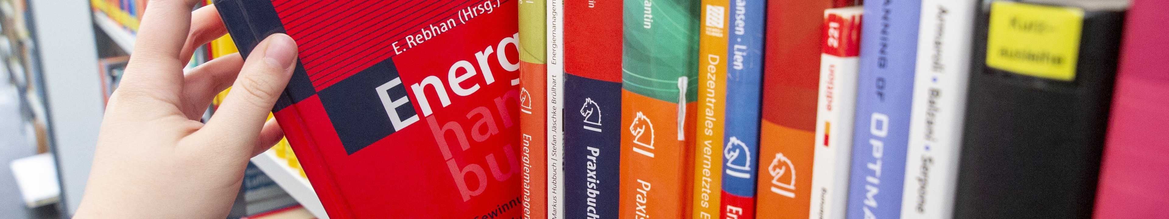 Hand nimmt Buch aus dem Regal